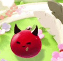 a red ball with horns on it is sitting on top of a green field .
