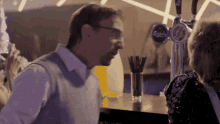 a man talking to a woman at a bar with a carlsberg beer tap