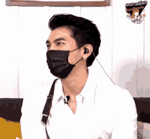 a man wearing a mask and ear buds has a sticker on his shirt that says ' knock knock '