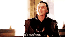 a man in a suit is smiling and says `` it 's madness '' .