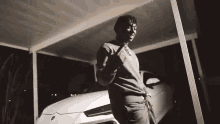 a man is standing in front of a white car in a driveway .