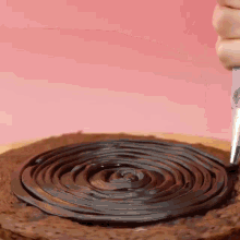 a person is frosting a chocolate cake with a knife .