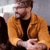 the man is wearing glasses and a yellow jacket .