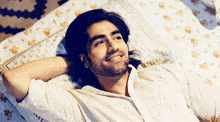 a man with long hair and a beard is laying on a bed