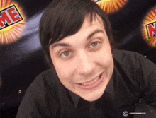 a young man in a black shirt smiles in front of a sign that says me