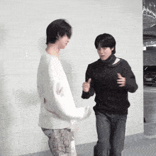 a man in a black sweater is standing next to a man in a white sweater