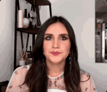 a woman with long dark hair is standing in front of a shelf and making a funny face .