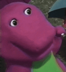 a close up of a purple stuffed animal with a green tail .