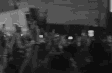 a blurry photo of a crowd of people walking down a street at night .