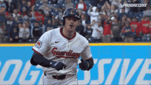 a baseball player wearing a guardians jersey is running on the field