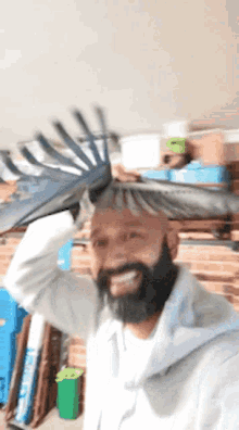 a man with a beard is holding a rake over his head and smiling
