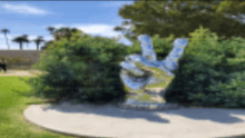 a statue of a hand giving a peace sign in front of a bush