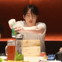 a man is pouring a can of soda into a pitcher at a table .