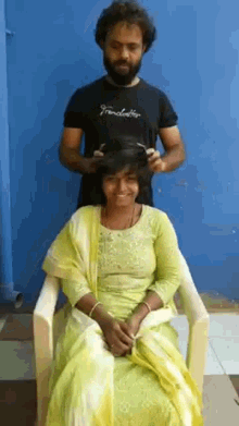 a woman in a green dress is getting her hair cut by a man wearing a black shirt that says fender