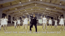 a man in a suit is dancing in front of a group of women with the words what the what the what the bunny do