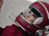 a woman wearing a red helmet with a white pillow on her face