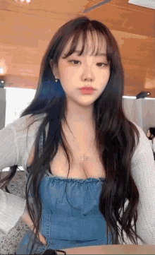 a woman with long hair is wearing a denim top and a white sweater