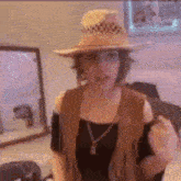 a woman wearing a hat and a vest is standing in front of a mirror .