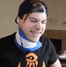 a man wearing a baseball cap and a neck brace is smiling while wearing headphones .