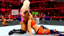two women are wrestling in a wrestling ring and one is laying on the other 's back .