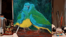 a painting of two blue and yellow birds is being painted on a canvas