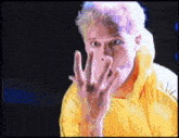 a man in a yellow hoodie is making a face with his hands