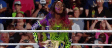 a woman is standing in a wrestling ring with a crowd watching .