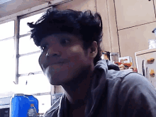 a man with a piercing in his nose looks at the camera in a kitchen