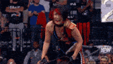 a woman in a wrestling outfit is standing in front of a crowd in a ring .