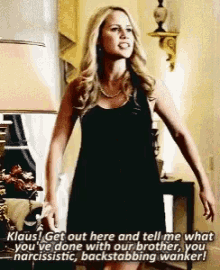 a woman in a black dress is standing in a living room talking to someone
