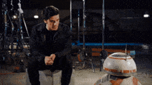 a man sits on a cooler next to a robot with ign written on the bottom