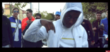 a man in a white hoodie is standing in front of a crowd of people