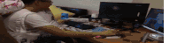 a man is sitting at a desk with a computer monitor and a keyboard .