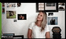 a woman in a white shirt is standing in front of a wall with pictures on it and the word office on it