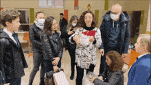 a group of people standing around a woman wearing a sweater that says " i love you "
