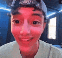 a young man wearing a hat with the word aqua on it is smiling and making a funny face .