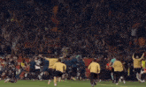 a group of soccer players running on a field with a crowd behind them