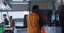 a man wearing a yellow mclaren shirt is standing in a garage .