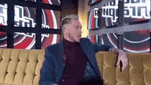 a man in a suit is sitting on a couch in front of a wall with a british flag on it .