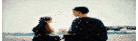 a man and a girl are sitting on the beach holding hands .