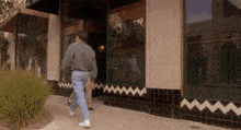a man walking down a sidewalk in front of a building that has a sign that says no parking