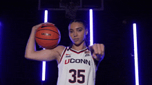 a woman is holding a basketball and pointing at the camera .