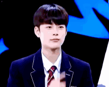 a young man in a suit is holding his finger to his lips .