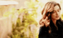 a woman is standing in front of a tree with her eyes closed and a blurry background .