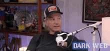 a man in a hat is sitting in front of a microphone in a room .