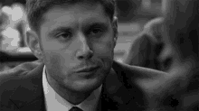a man in a suit and tie is looking at another man .