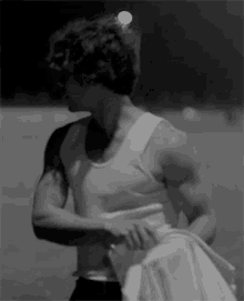 a black and white photo of a man wearing a white tank top .