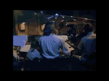 a group of people are sitting in front of a stage playing instruments