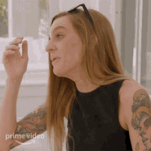 a woman with a tattoo on her arm is wearing sunglasses and a black tank top with the words prime video on the bottom