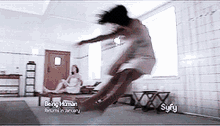 a woman is jumping in the air in a room with being human written on it